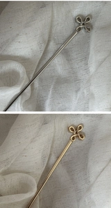 Detail of silver and gold alloy hair sticks with refined lucky knot clover tops