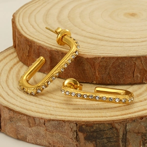Elegant gold-plated U-shaped earrings with zircon crystals on natural wood slices