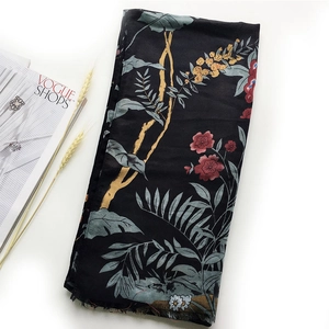 Detail of folded black satin scarf with floral bird print alongside Vogue magazine