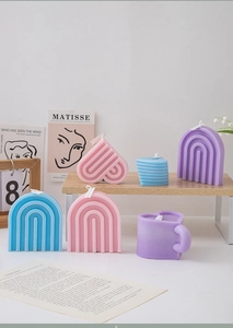 Artistic arrangement of heart-shaped and arched scented candles in soft pastel tones