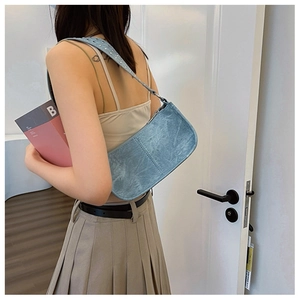 Detail of light blue punk style shoulder bag with metallic finish and studded strap