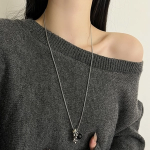 Long collier argenté avec pendentif en pierre naturelle porté sur pull gris