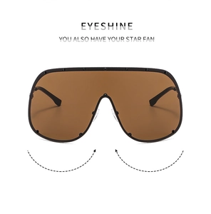 Detail view of brown shield sunglasses with black frame and decorative studs on white background