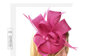 Detail of rose red fascinator pillbox hat with feathers and pearl accents for party wear