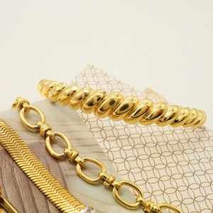 Detail of 18K gold-plated jewelry set featuring croissant twist and snake chain texture