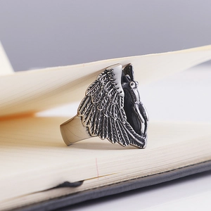 Macro detail of vintage silver angel wing ring showing intricate feather textures on steel