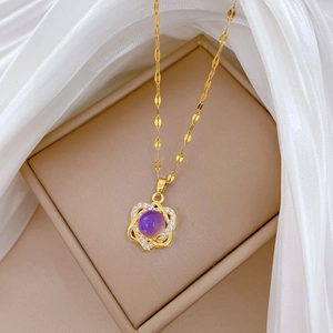 Detailed close-up of a gold clover necklace with purple gemstone and sparkling crystals