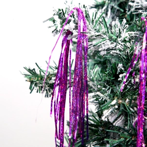 Fuchsia holographic tinsel fringe hanging on snowy Christmas tree branches for party decor