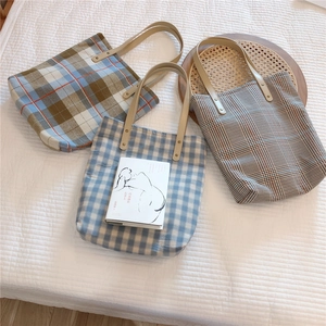 Close-up of vintage plaid canvas tote bags with premium brown leather handles and rivets