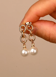 Close-up of interlocking gold chain links with an elegant white pearl drop earring
