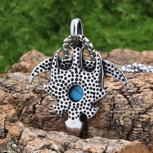 Detail of vintage eagle steel pendant with blue turquoise stone on rustic wood bark