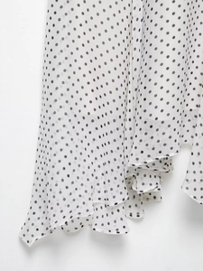Detailed macro view of polka dot fabric texture and asymmetrical hemline of a halter dress