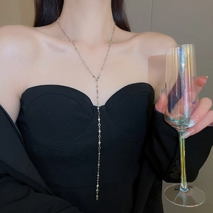 Silver Y-shaped tassel necklace with heart charms worn by a model in a formal setting