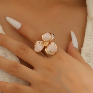 Dettaglio dell'anello a fiore con petali rosa e bordi dorati indossato sulla mano