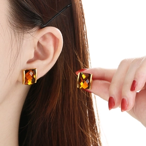 Detail of square amber gemstones set in gold bezels worn by a model in a studio setting