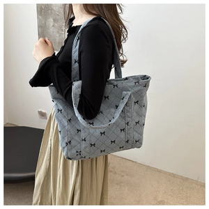 Detail of light blue quilted tote bag with black bow patterns and diamond stitching