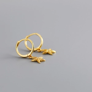 Detailed close-up of golden starfish charms dangling from elegant S925 sterling silver hoops