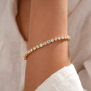 Nahaufnahme eines goldfarbenen Tennisarmbands mit funkelnden Kristallen am Handgelenk