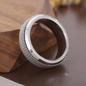 Macro d'une bague en acier inoxydable argenté avec un anneau rotatif à texture tressée