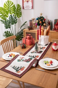 Detailed Christmas table runner with red plaid edges and festive tree motifs on wood table