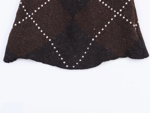 Close-up of knit fabric showing dark brown and black diamond pattern with white dotted lines