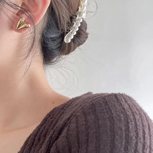 Close-up of minimalist gold heart stud earring worn on ear showing size and shiny finish