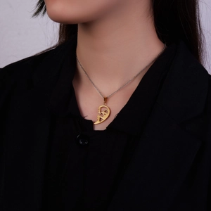 Detail of gold heart puzzle pendant engraved with I Love You on a model in black blazer
