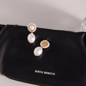 Baroque pearl flower earrings in stainless steel with gold finish on black leather base
