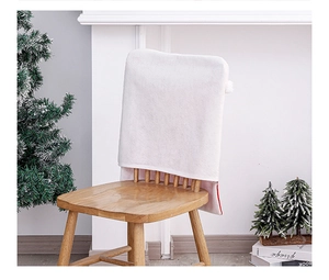 Detail of white velvet Christmas chair cover featuring red trim and soft fabric texture