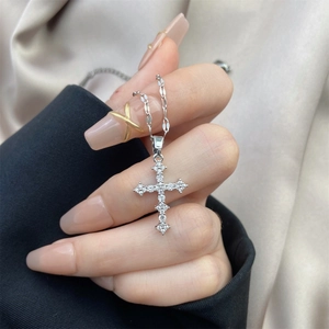 Detailed view of silver-plated cross pendant with sparkling zircons on soft silk fabric