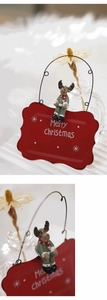 Close-up of a red metal Merry Christmas plaque with a cute reindeer doll and floral decor