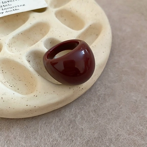 Close-up of a burgundy resin dome ring displayed on a minimalist ceramic jewelry tray