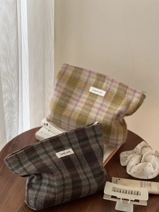 Macro shot of plaid wool makeup bags on a wooden table with simple wish labels