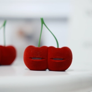 Primer plano de joyero con forma de cereza en terciopelo rojo para anillos