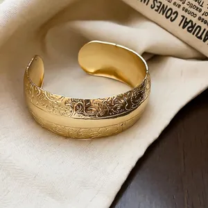 Bracelet manchette doré élégant avec motifs floraux vintage sur tissu crème
