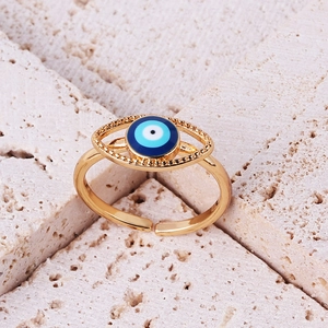 Macro detail of gold evil eye open ring with blue enamel inlay on marble background