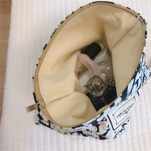 Top view of open floral cotton cosmetic bag showing spacious beige canvas interior