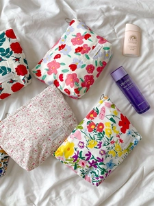 Flat lay of four floral cotton makeup bags with zippers on a white sheet background