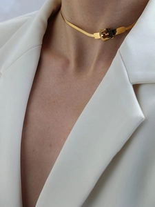 Dettaglio della collana dorata a serpente con fibbia su modella in blazer bianco