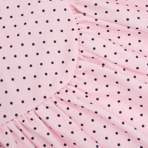 Macro detail of pink fabric with black polka dots and delicate pleated texture