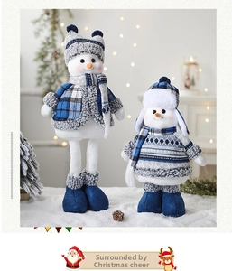 Detail view of two blue and white plush Christmas snowmen with plaid scarves and ear muffs
