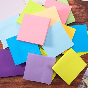 Colorful 3x3 inch fluorescent sticky notes scattered on a dark wooden background