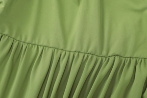 Detail of green ribbed knit fabric showing soft pleats and professional stitching texture