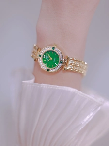 Close-up of luxury women's gold watch with green dial and sparkling diamond bezel detail