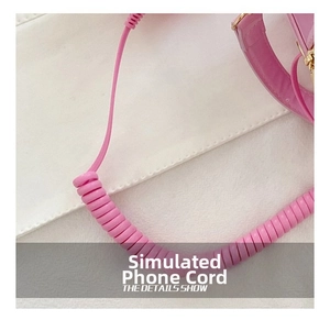 Close-up of pink spiral phone cord strap with metallic connectors for crossbody bag
