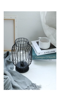 Detailed view of a black metal cage LED lantern on a cozy tabletop with books