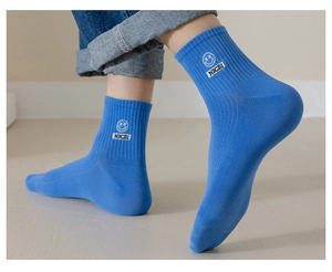 Close-up of bright blue ribbed knit crew socks featuring white smiley face and NICE embroidery