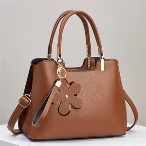 Brown lychee leather tote bag with floral charm and adjustable shoulder strap