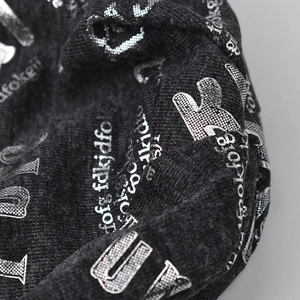 Close-up macro detail of metallic silver letter print on a premium black knitted slouchy beanie