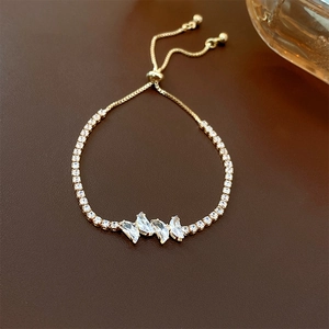 Close-up of golden adjustable slider bracelet with marquise-cut zircons on leather